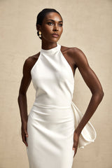Woman wearing a white bandage dress with an oversized bow detail and fitted silhouette