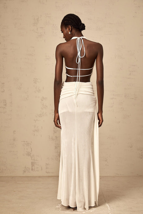 Woman wearing a white halterneck backless maxi dress standing in a relaxed pose