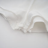 Woman wearing a white halterneck mini dress with ruffled details and a fitted silhouette