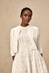 Woman wearing a white knitted cardigan with ruffled details and long sleeves