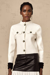 Woman wearing a white knitted jacket with contrasting color details and a zipper closure
