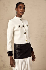 Woman wearing a white knitted jacket with contrasting color details and button closure