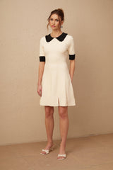 Woman wearing a white knitted mini dress with split hem detail and short sleeves