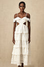 Woman wearing a white lace midi dress with openwork pattern standing in a neutral background