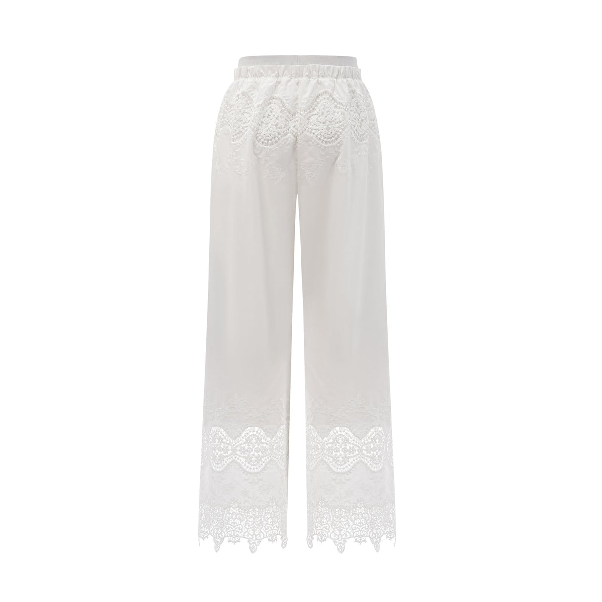 Woman wearing a white lace trimmed cropped top and matching trousers with cutout details