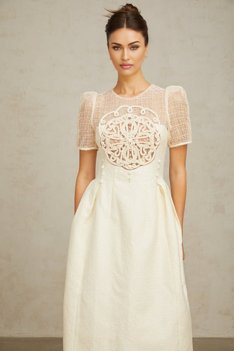 Woman wearing a white midi dress with braided panel details and sleeveless design