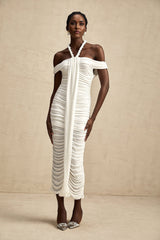 Woman wearing a white midi dress with braided rope details and short sleeves standing against a neutral background