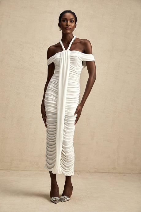 Woman wearing a white midi dress with braided rope details and short sleeves standing against a neutral background