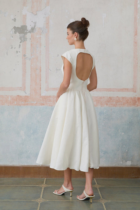 Woman wearing a white midi dress with cap sleeves and open back design