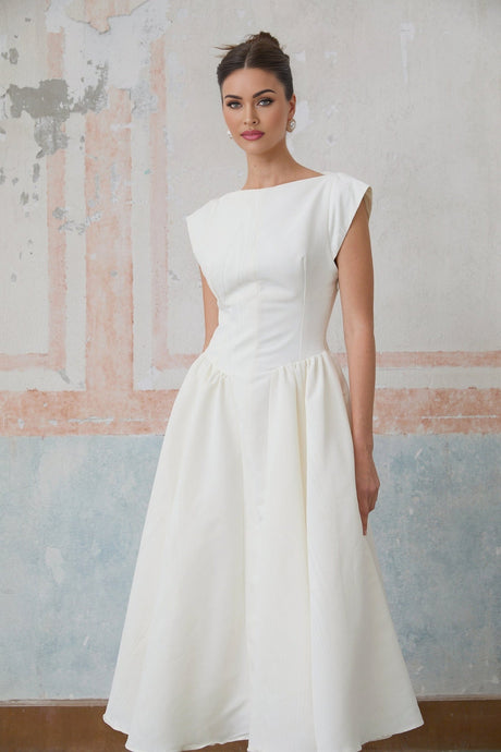 Woman wearing a white midi dress with cap sleeves and open back standing in relaxed pose