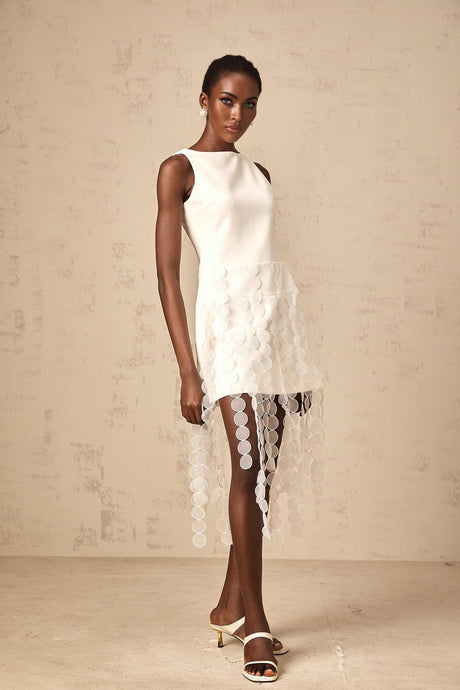 Woman wearing a white midi dress with circular disc design and fringe details