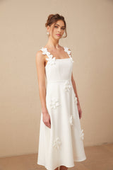 Woman wearing a white midi dress with faux flower details and a square neckline