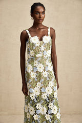 Woman wearing a white midi dress with floral embroidery and cutout details throughout the fabric