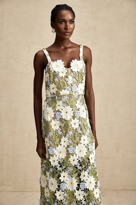 Woman wearing a white midi dress with floral embroidery and cutout details throughout the fabric