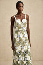Woman wearing a white midi dress with floral embroidery and cutout details throughout the fabric