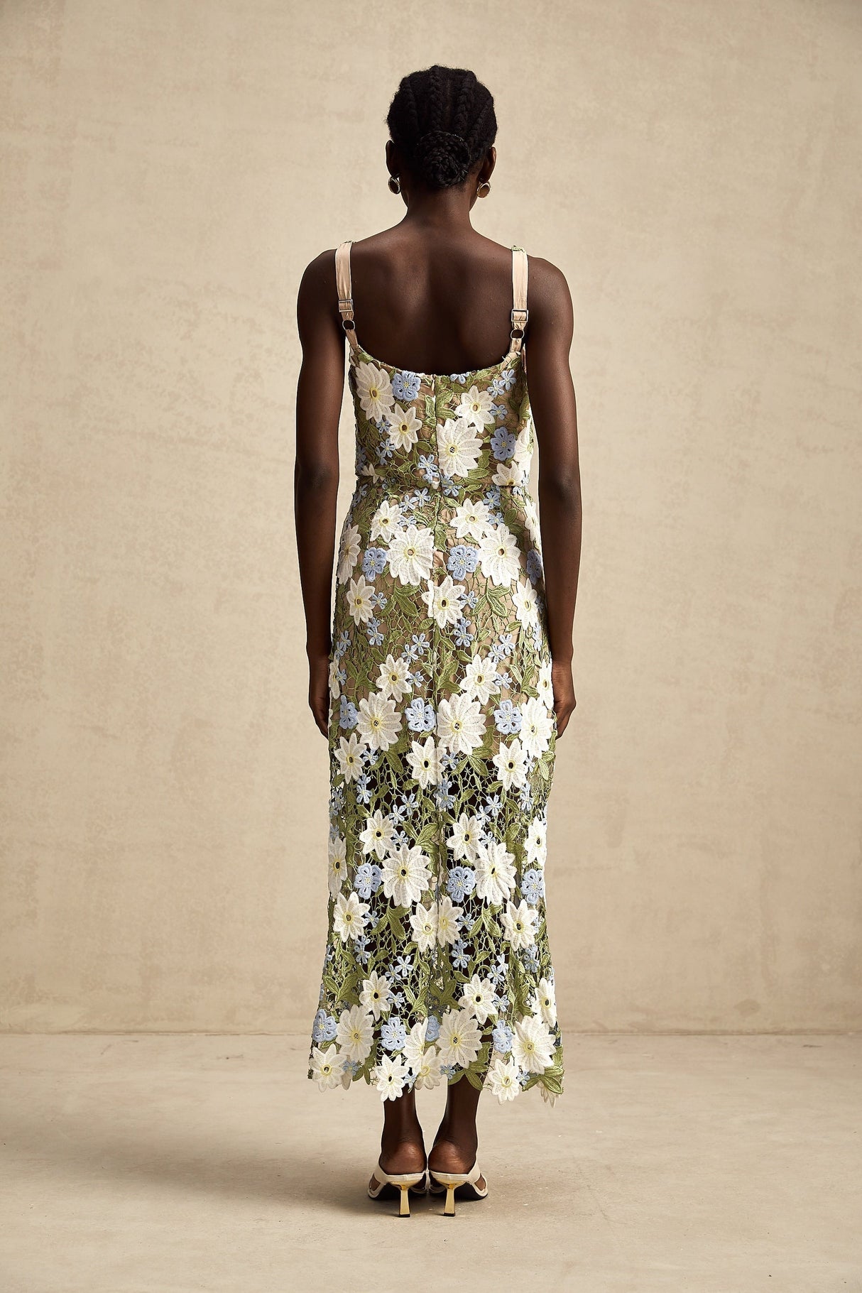 Woman wearing a white midi dress with floral embroidery and cutout details