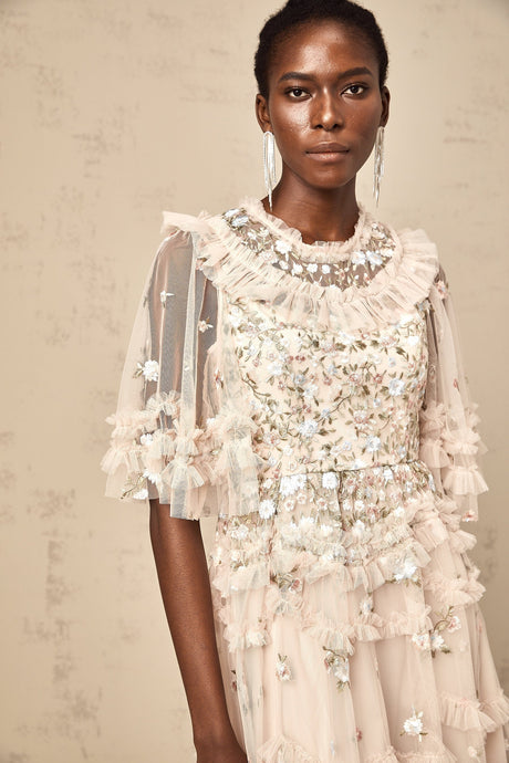 Woman wearing a white midi dress with floral embroidery and tiered ruffles