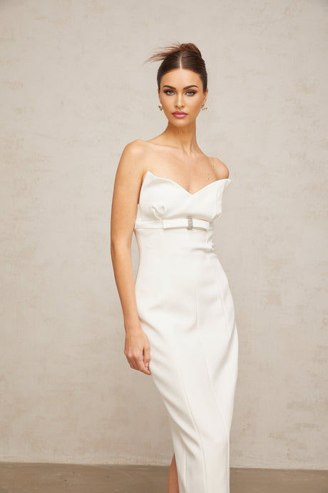 Woman wearing a white midi length corset dress with bow details and a fitted silhouette