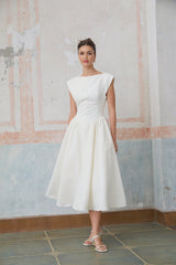 Woman wearing a white midi length dress with cap sleeves and an open back design