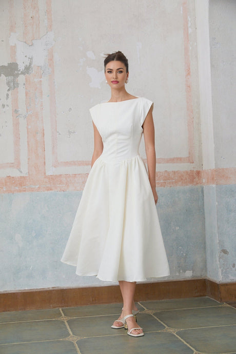 Woman wearing a white midi length dress with cap sleeves and an open back design