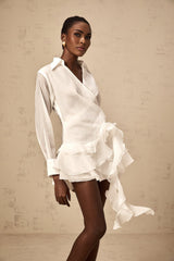 Woman wearing a white mini dress with sheer floral details and ruffles
