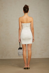 Woman wearing a white offshoulder mini dress with sequin embellishments