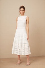 Woman wearing a white sleeveless knitted midi dress with cutout details standing in a neutral pose