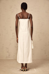 Woman wearing a white sleeveless midi dress with three dimensional floral petal details