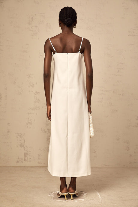 Woman wearing a white sleeveless midi dress with three dimensional floral petal details