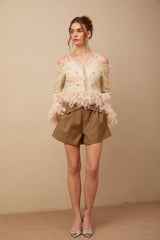 Woman wearing an off shoulder tweed top with feather trim at the neckline