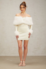 Woman wearing an offwhite faux fur fine knit top and matching skirt set standing against a plain background