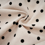 Woman wearing beige polka dot mini dress with puff sleeves and gathered skirt