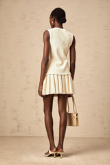 Woman wearing beige sequined knit vest top with matching skirt standing in casual pose