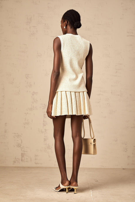 Woman wearing beige sequined knit vest top with matching skirt standing in casual pose