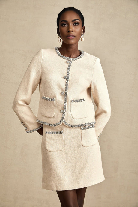 Woman wearing beige tweed cardigan and matching skirt set with crystal embellishments