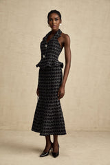 Woman wearing black and white checked tweed vest top paired with matching skirt set against plain background