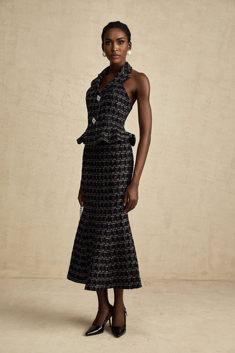 Woman wearing black and white checked tweed vest top paired with matching skirt set against plain background