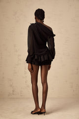 Woman wearing black asymmetric tulle blouse and matching skirt set named Andrea