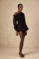 Woman wearing black asymmetric tulle blouse and matching skirt set