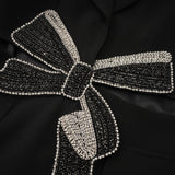 Woman wearing black blazer with cutout details and decorative bow accent
