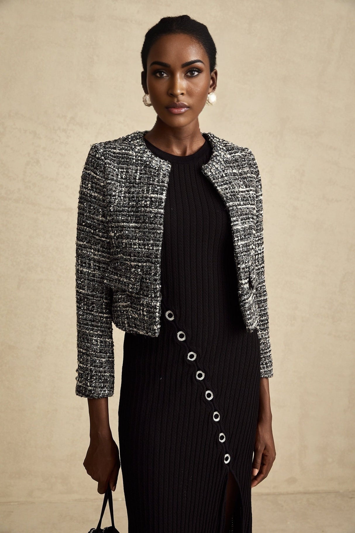 Woman wearing black bouclé tweed jacket with textured fabric and classic tailored design