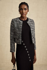 Woman wearing black bouclé tweed jacket with textured fabric and classic tailored design