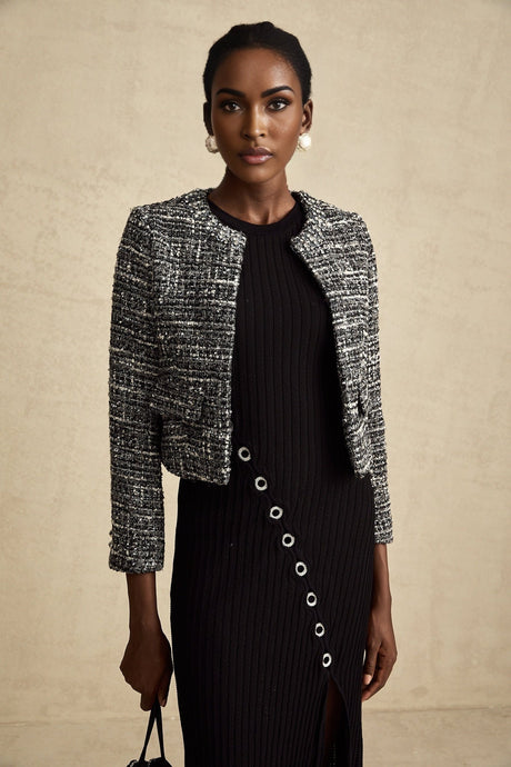 Woman wearing black bouclé tweed jacket with textured fabric and classic tailored design