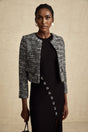 Woman wearing black bouclé tweed jacket with textured fabric and classic tailored design