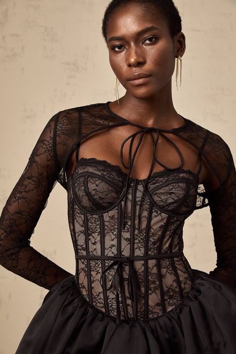 Woman wearing black floral lace sleeveless vest over matching dress with delicate floral pattern