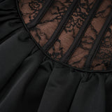 Woman wearing black floral lace sleeveless vest over matching dress with floral lace pattern
