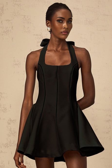 Woman wearing black halterneck mini dress with bow detail at neck