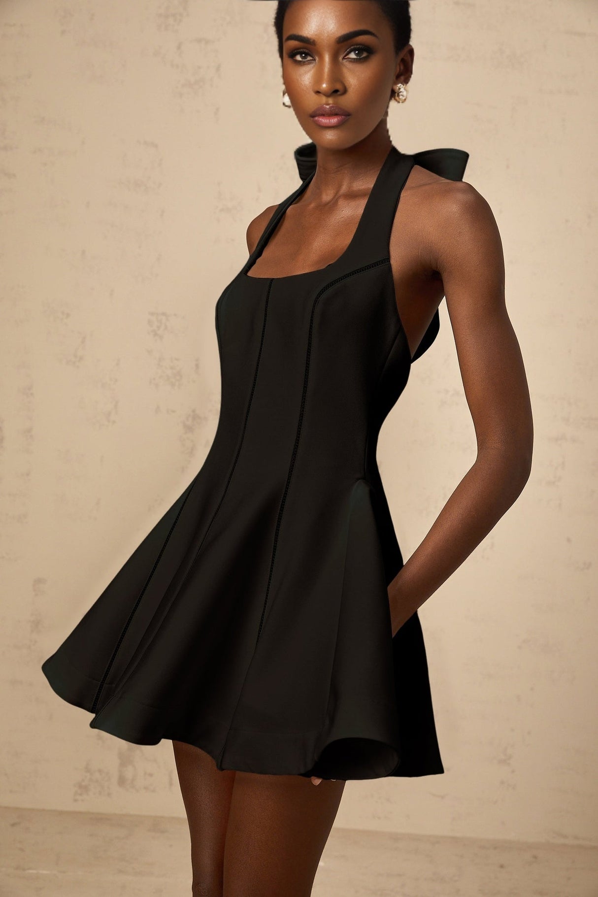 Woman wearing black halterneck mini dress with bow detail at neckline