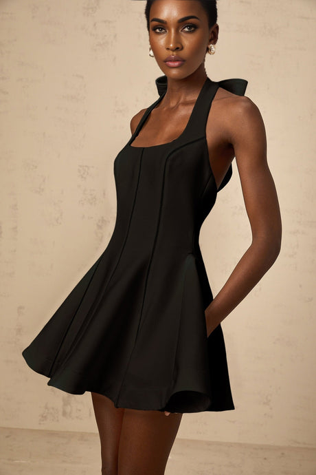 Woman wearing black halterneck mini dress with bow detail at neckline