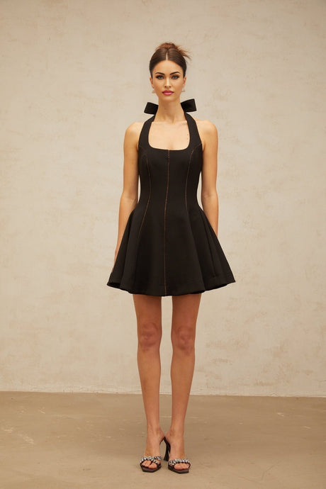Woman wearing black halterneck mini dress with bow detail